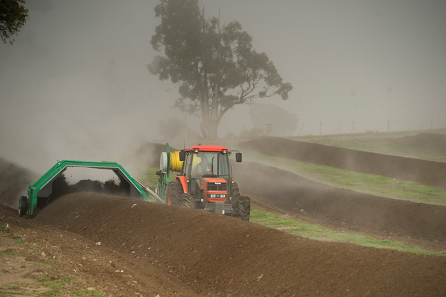 A tractor makes dirt rows on a farm